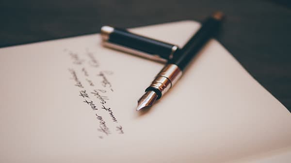 Fountain pen placed on paper with handwritten note displayed on the page